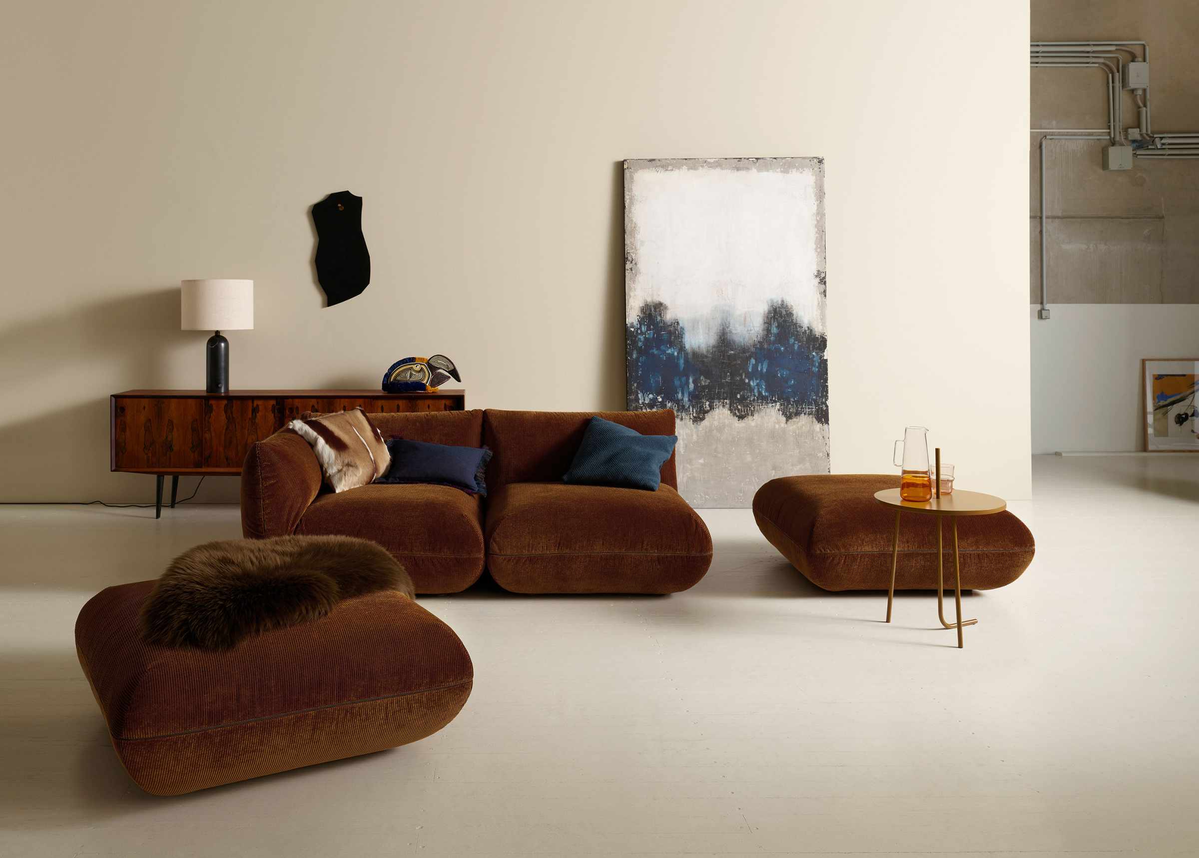 Brauner Jalis Hocker als Teil einer Wohnlandschaft mit Cordbezug und Beistelltisch.