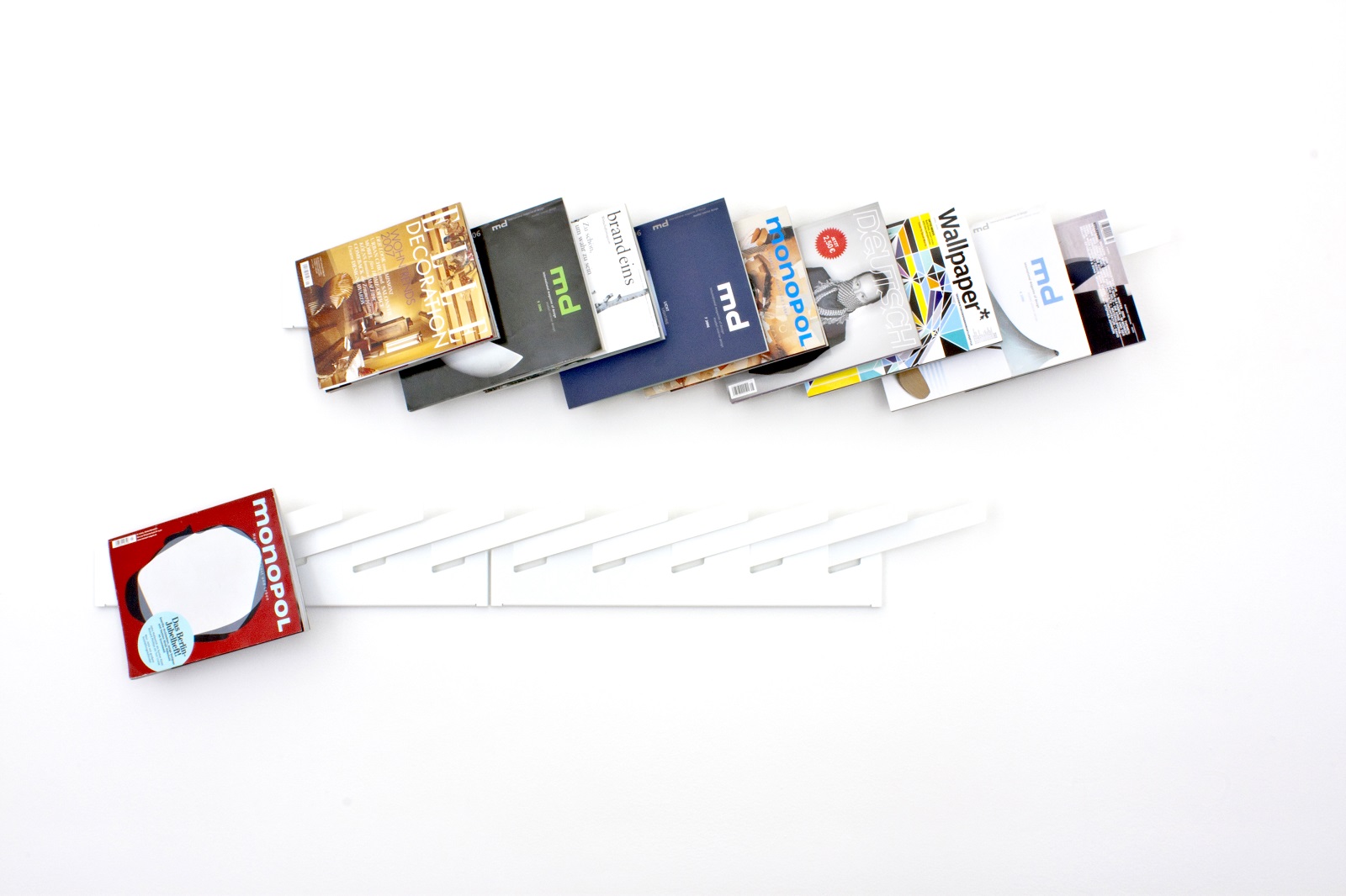 Weißes Zeitschriftenregal mit Magazinen wie Monopol, Wallpaper und md, modernes Wandregal für Wohnzimmer und Büro.