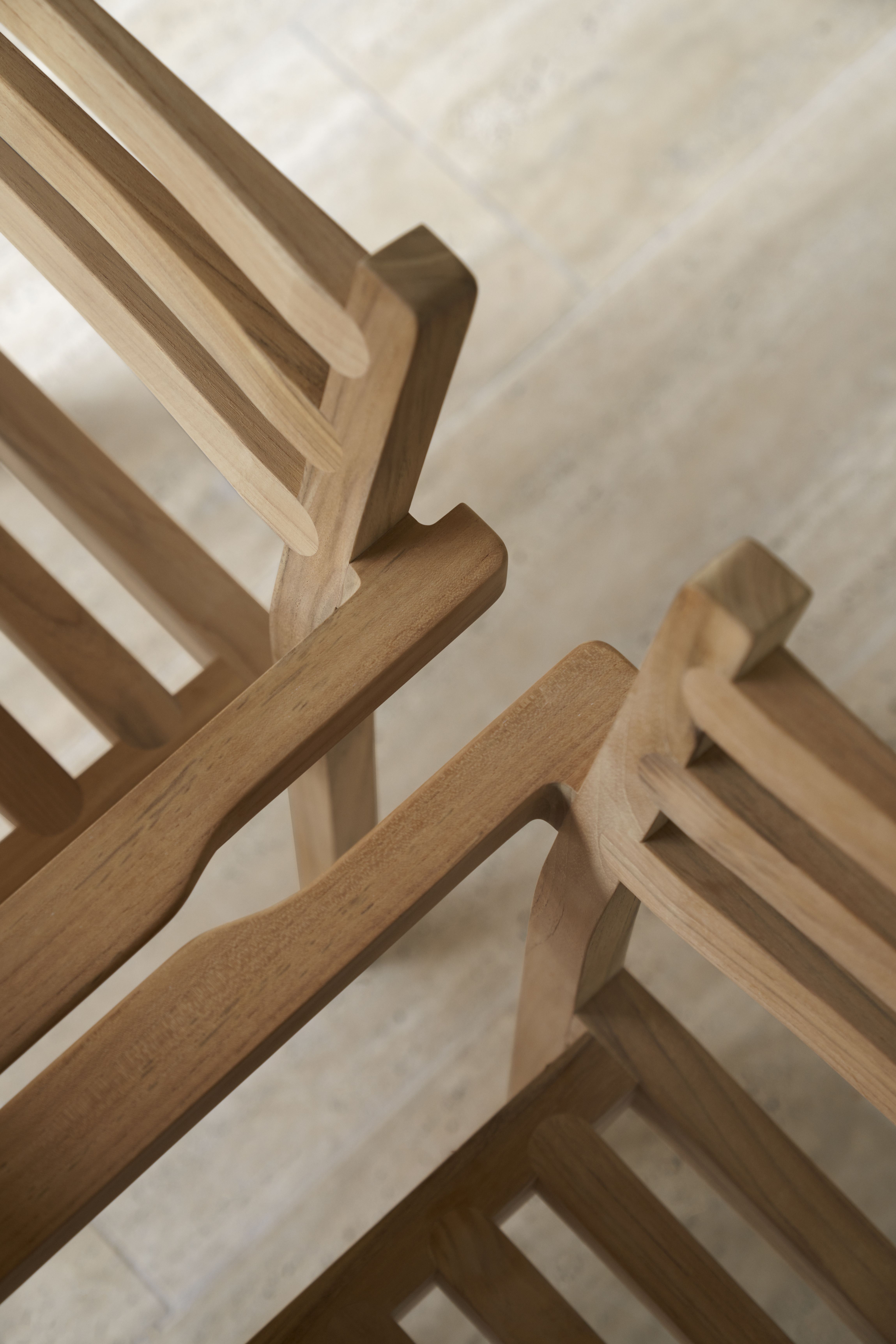 Detailaufnahme von zwei AH502 Armlehnstühlen aus Teakholz von Carl Hansen, ideal für den Außenbereich.
