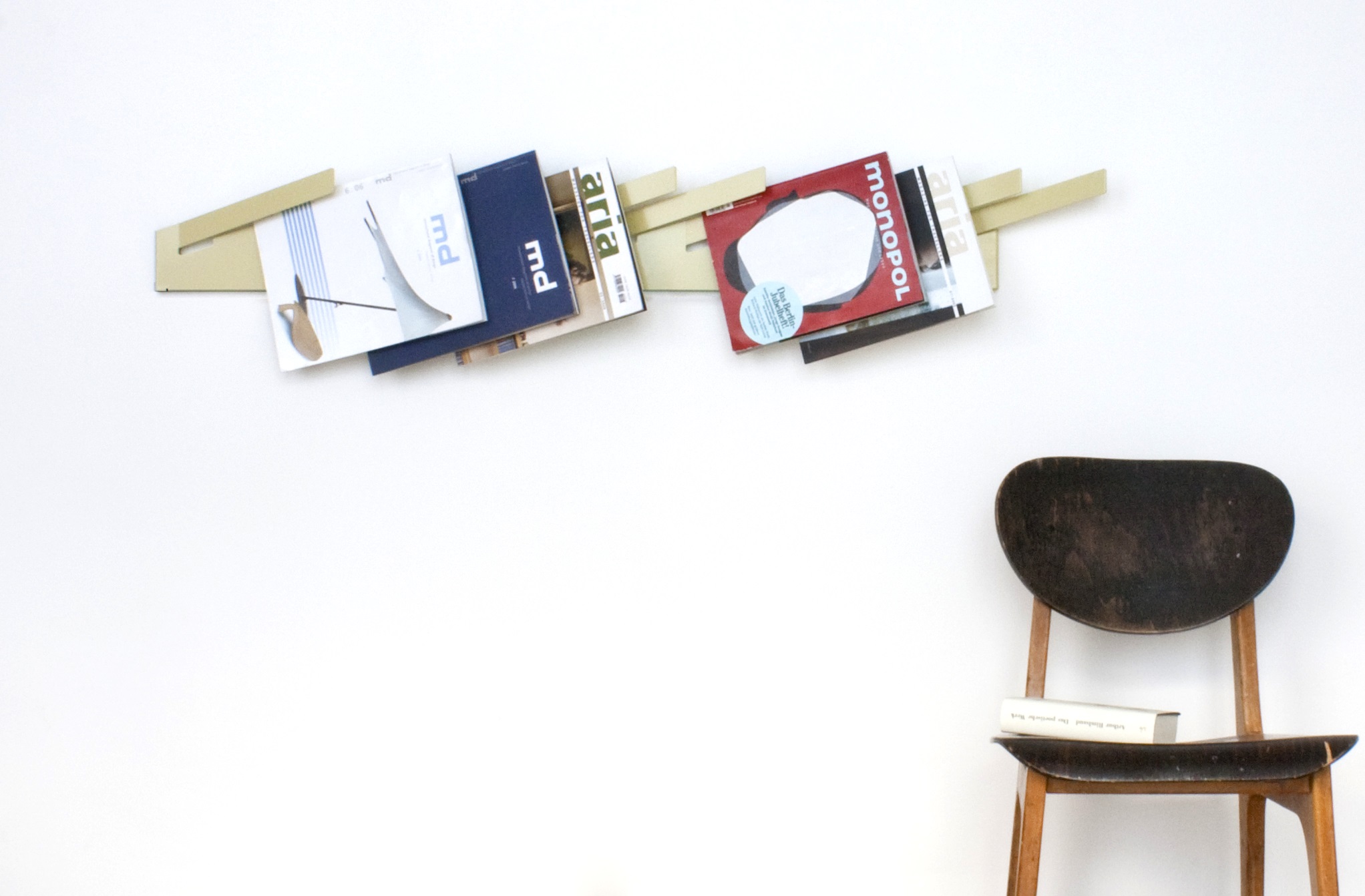 Beige Design Wandgarderobe mit Magazinen und Stuhl im Hintergrund, moderne Flurgarderobe für Zeitschriften.