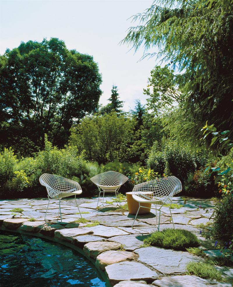 Drei Bertoia Diamond Sessel Outdoor von Knoll International auf einer Terrasse am Pool.