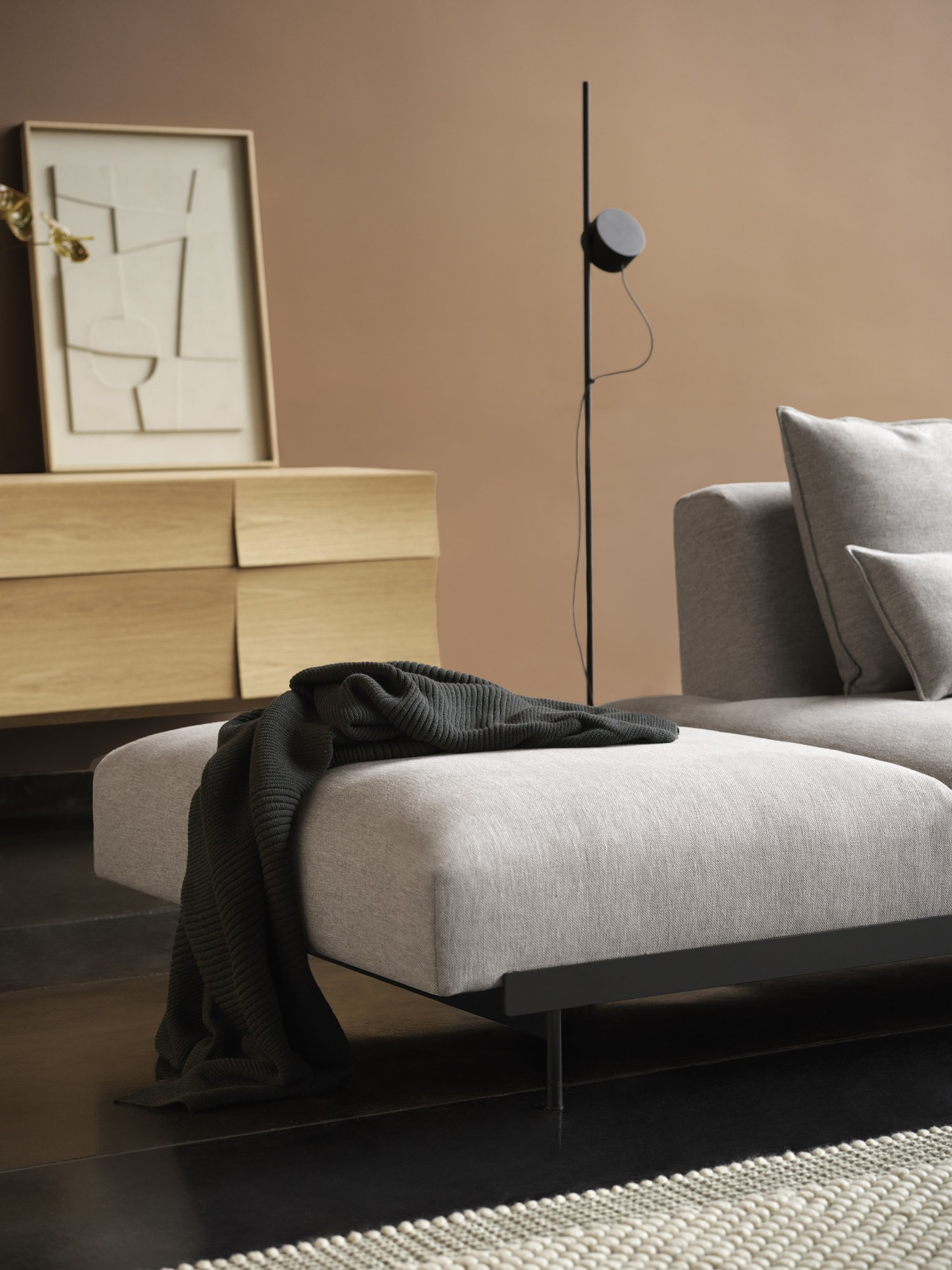 Helles Holz Sideboard, möglicherweise Muuto Reflect, mit minimalistischer Kunst und grauem Sofa im Wohnzimmer.