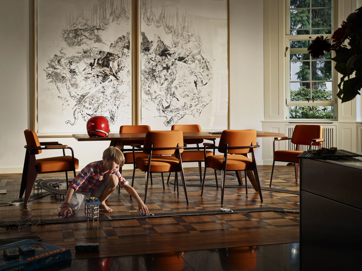 Oranger Fauteuil Direction Sessel von Vitra um einen Holztisch mit spielendem Kind im Wohnzimmer.