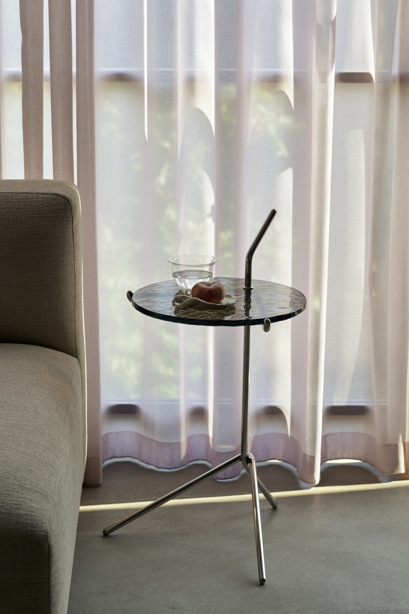 AndTradition Halten Beistelltisch SH9 neben einem Sofa, mit Wasserglas und Pfirsich. Moderner, runder Tisch.
