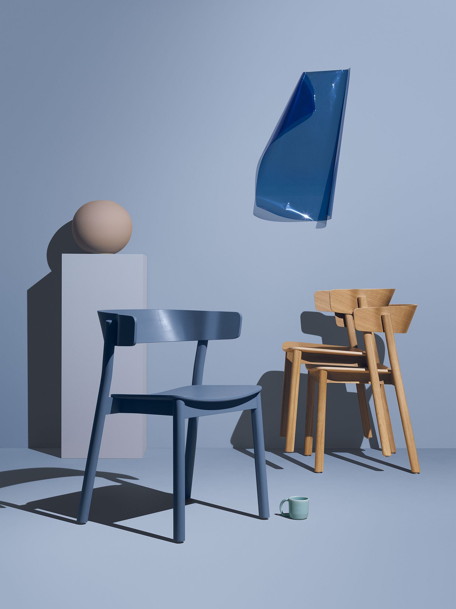 Blauer Enfold Chair Stuhl von Mizetto neben zwei Holzstühlen, minimalistisches Möbeldesign für Esszimmer und Büro.