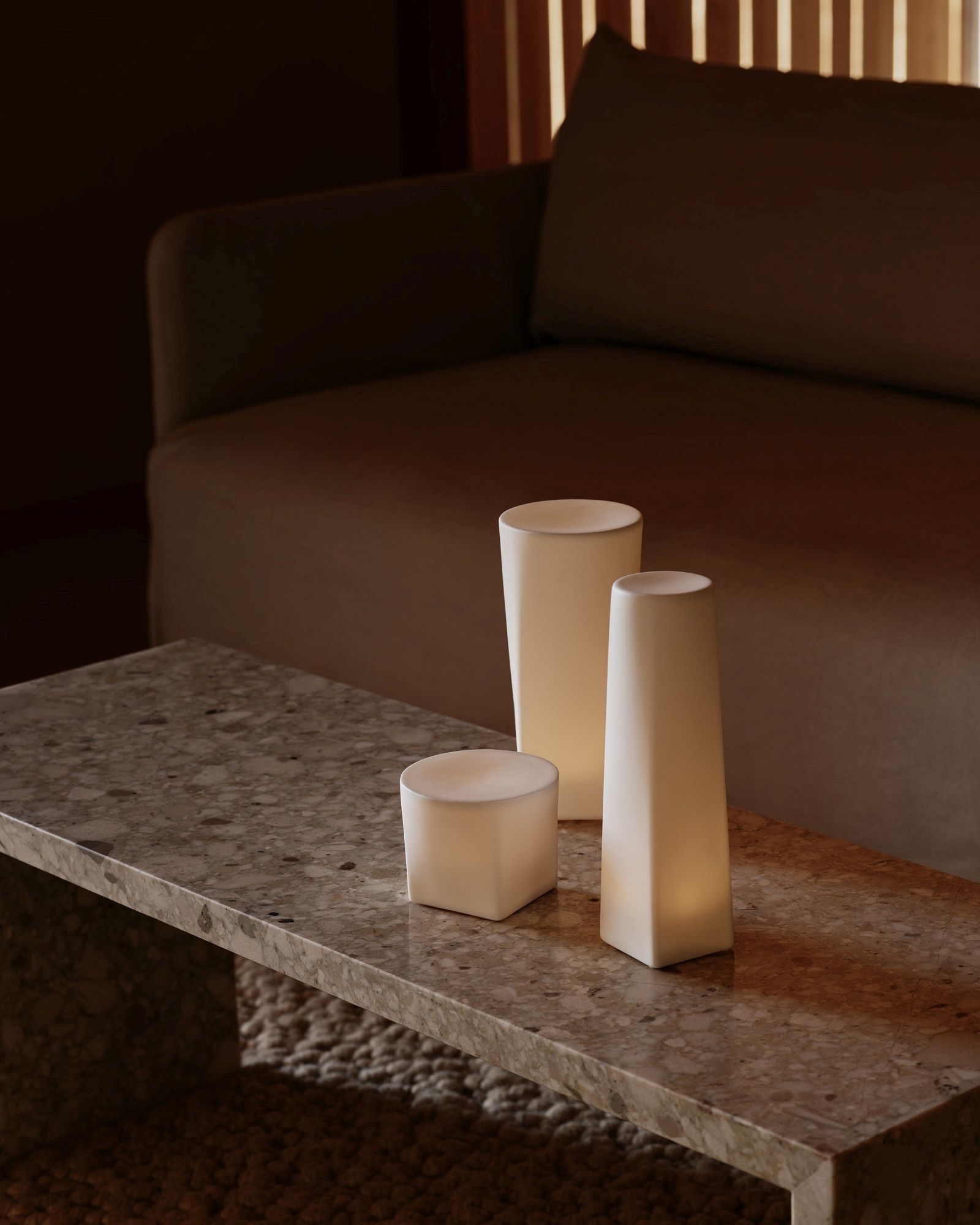 Audo Copenhagen Offset Sofa im Wohnzimmer mit minimalistischen Tischleuchten auf einem Marmortisch.