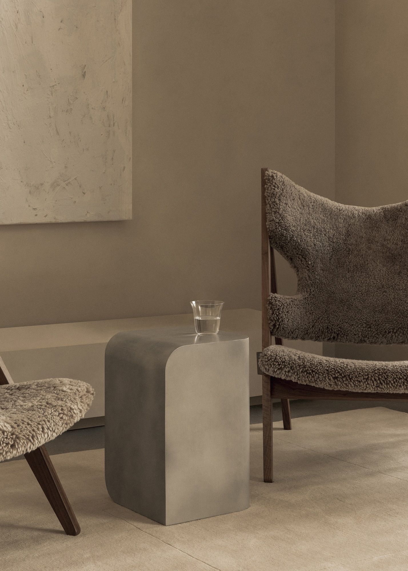 Audo Copenhagen Volume Side Table Beistelltisch aus Metall mit Wasserglas neben Sessel.