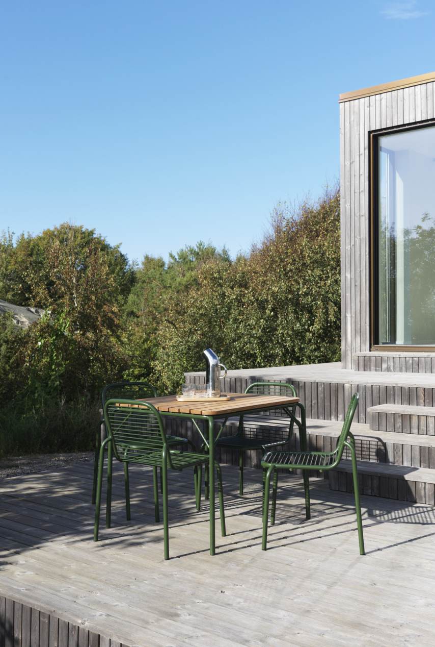 Normann Copenhagen Vig Chair Outdoor Set mit Tisch und vier grünen Stühlen auf Holzterrasse.