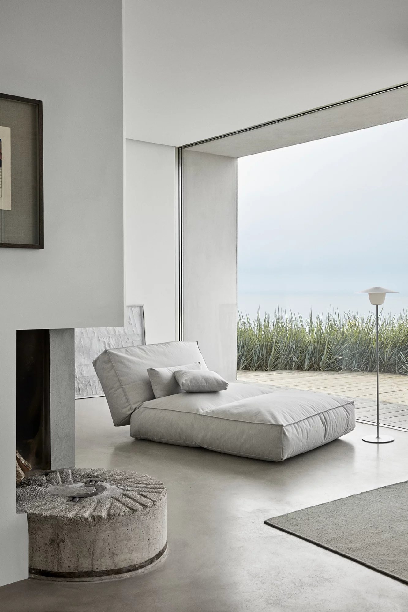Helles Interieur mit Blomus Stay Day Bed, grauem Outdoor Tagesbett und Meerblick.