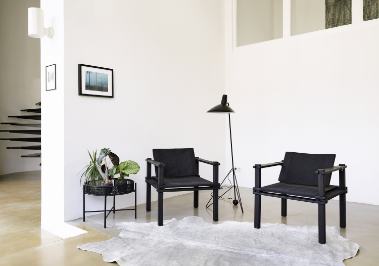 Zwei schwarze Farmer Sessel Outdoor Cor mit Kissen auf einem hellen Teppich in modernem Wohnzimmer.