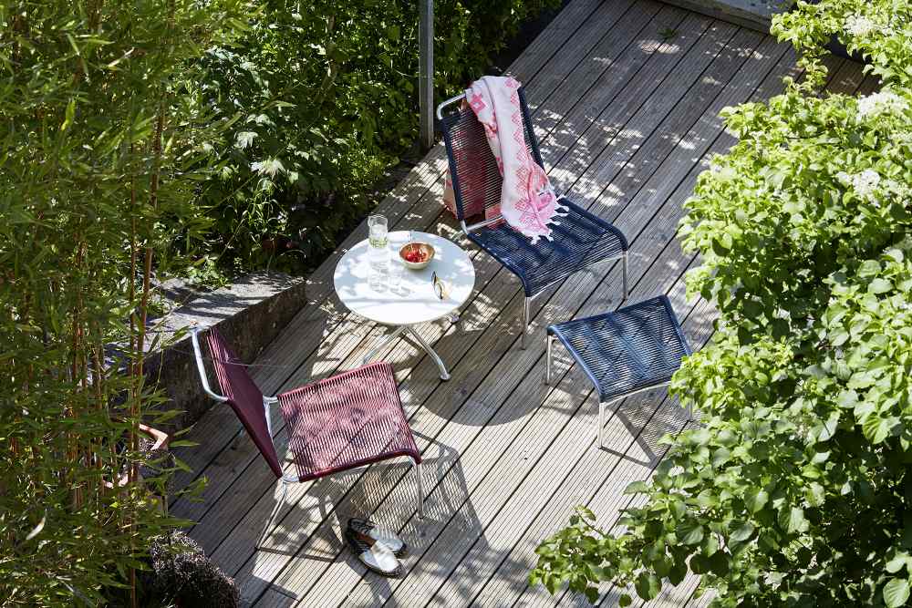 Altorfer Stuhl Outdoor Embru in Verkehrsrot auf Holzterrasse mit Tisch und grüner Umgebung.