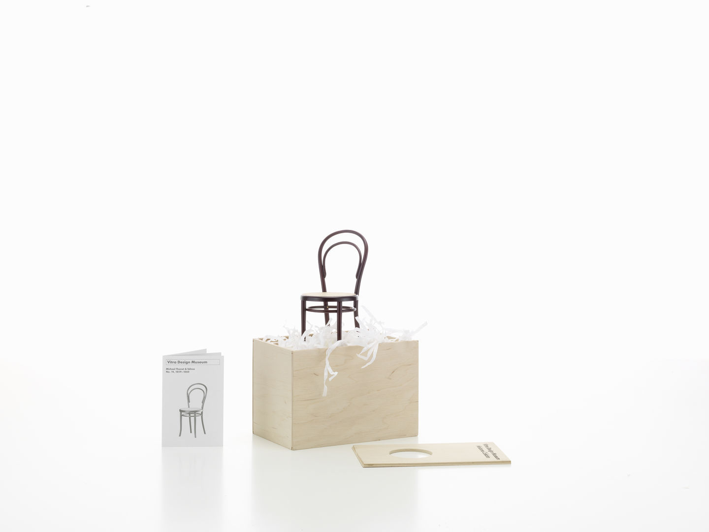 Miniatur Stuhl No. 14 von Vitra, Bugholzstuhl Designklassiker, auf hellem Holzwürfel mit Broschüre.