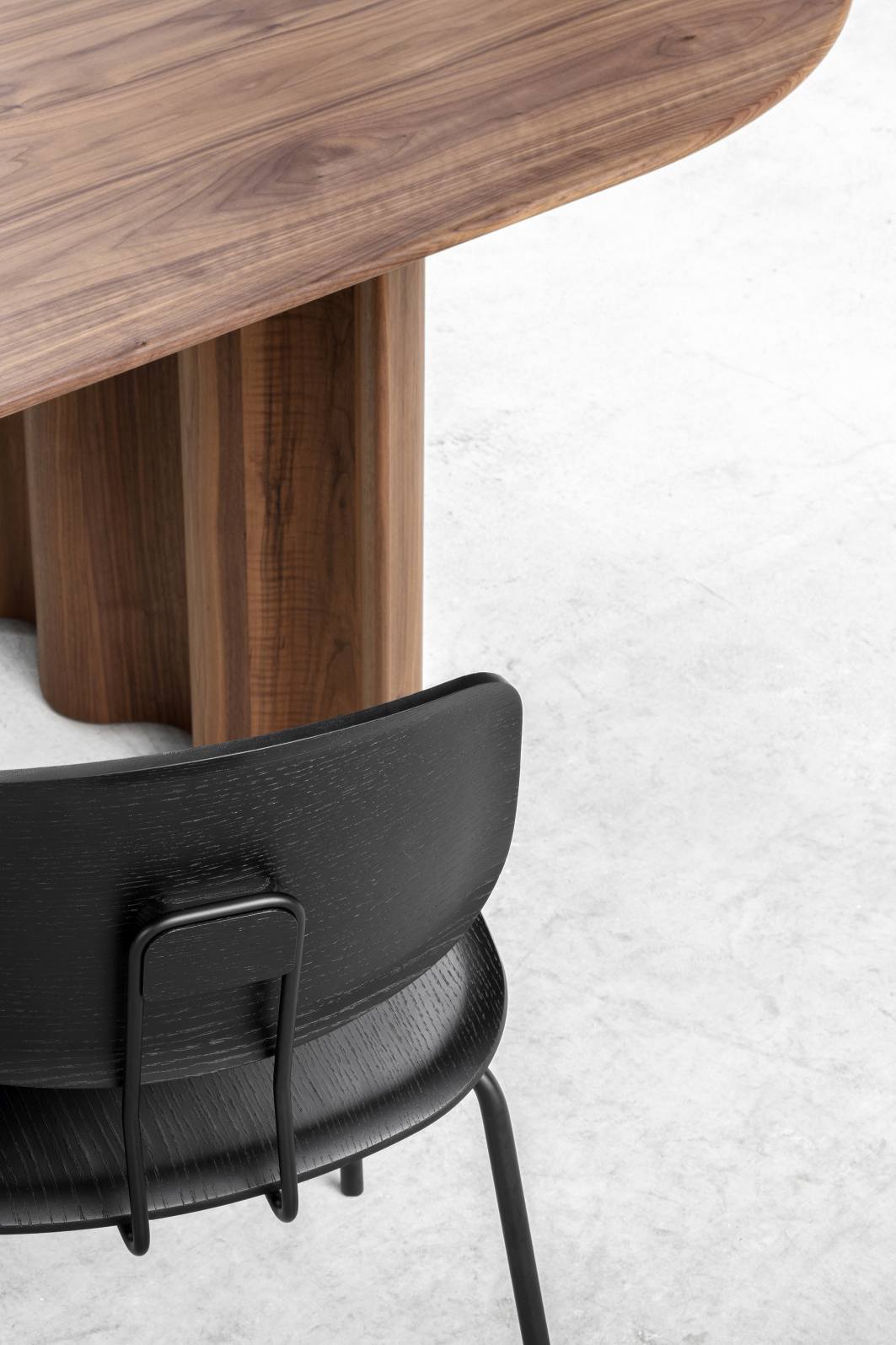 Schwarzer Okito Ply Dining Chair Stuhl mit Holz-Esstisch im Hintergrund, moderne Möbel für Esszimmer.