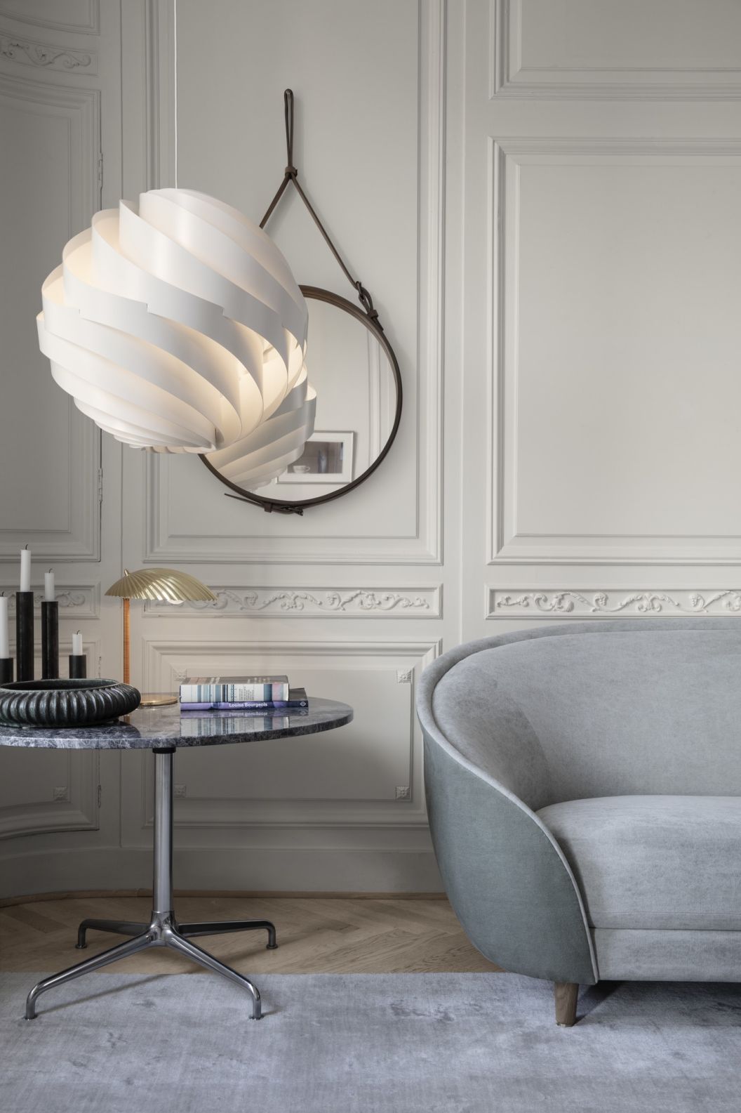 Adnet Circular Spiegel von Gubi in stilvollem Interieur mit Pendelleuchte und Marmortisch.