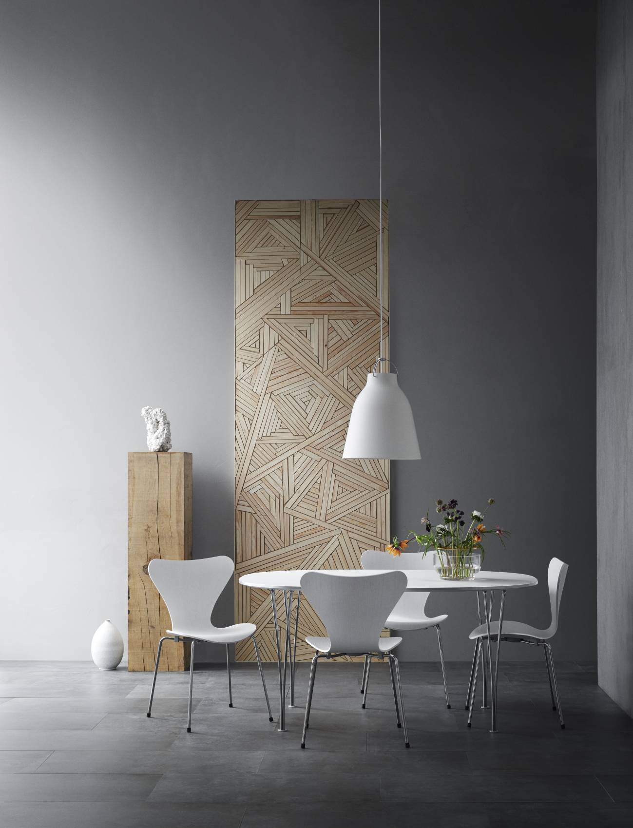 Minimalistischer Essbereich mit rundem Fritz Hansen Tisch, weißen Stühlen und Pendelleuchte.