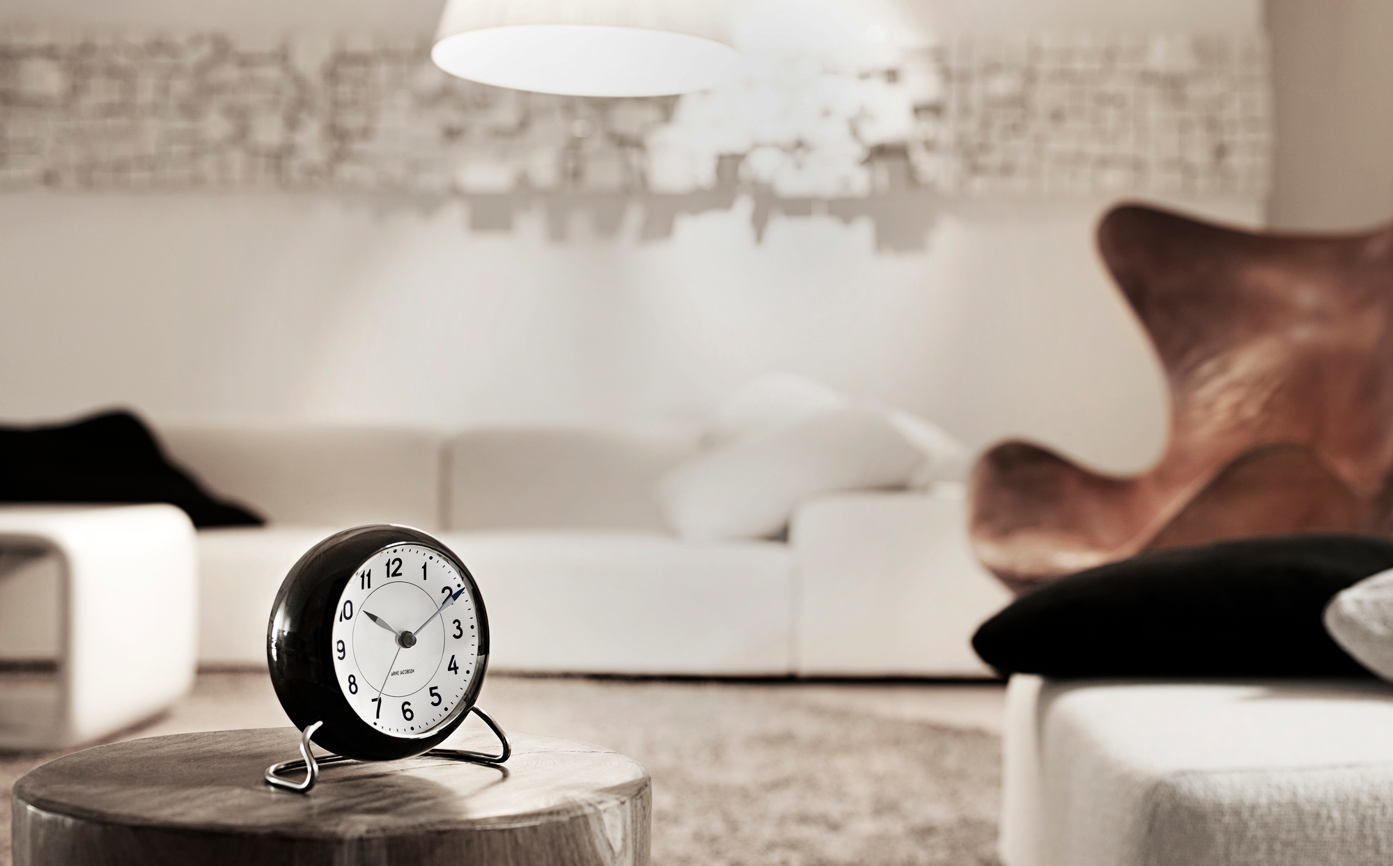 Arne Jacobsen Station Tischuhr von Rosendahl Timepieces in Schwarz-Weiss auf einem Holztisch im Wohnzimmer.
