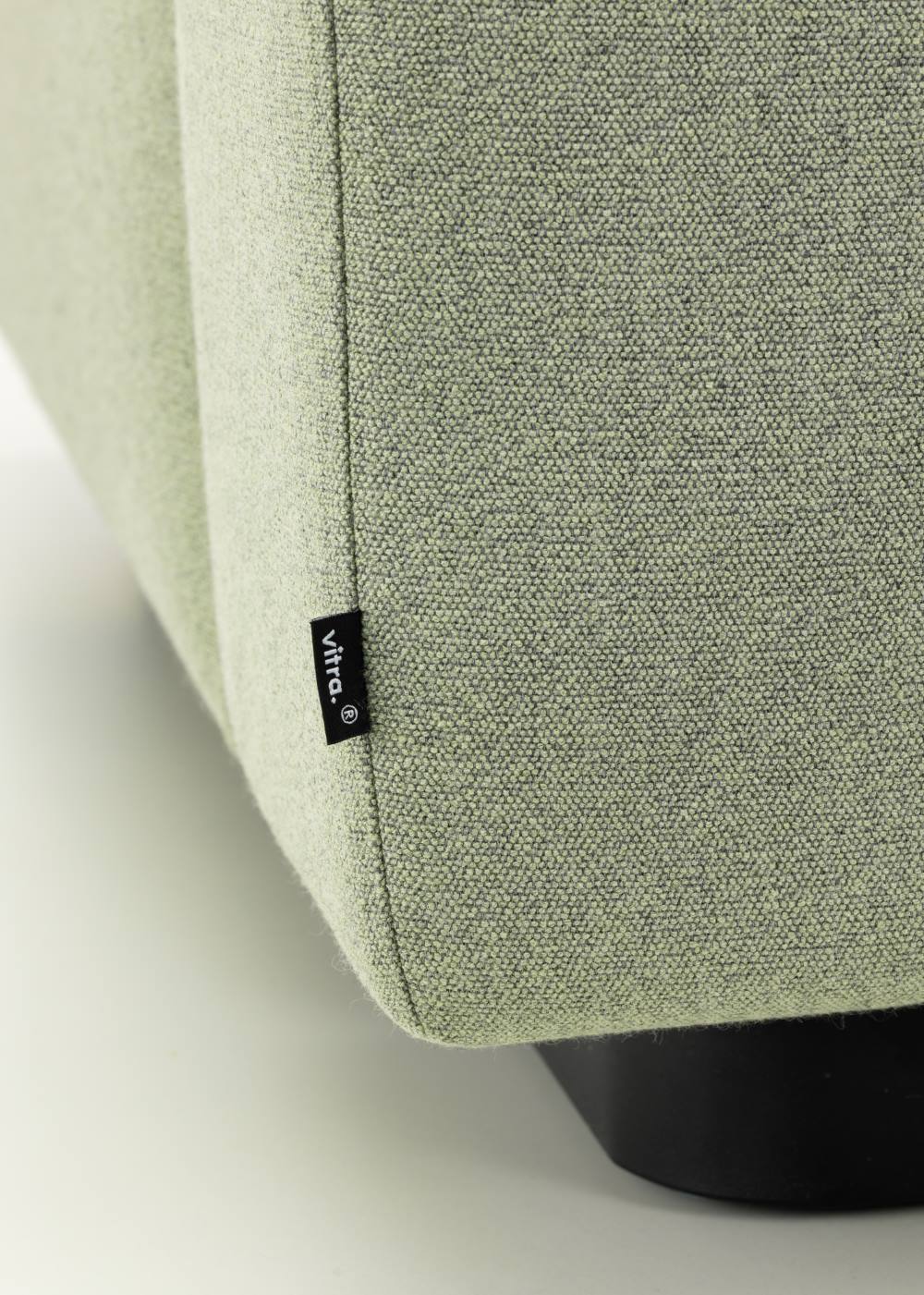 Detailaufnahme vom hellgrünen Vitra Sofa mit Stoffbezug und schwarzem Fuß, Label "vitra." sichtbar.