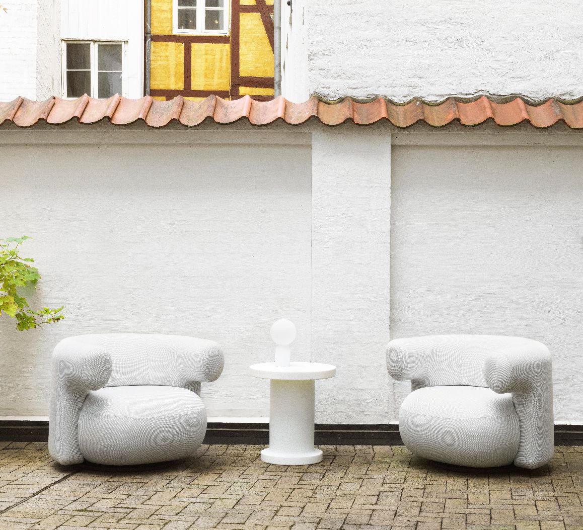 Normann Copenhagen Yo Lamp Tischleuchte als Akkuleuchte zwischen zwei Sesseln im Außenbereich.