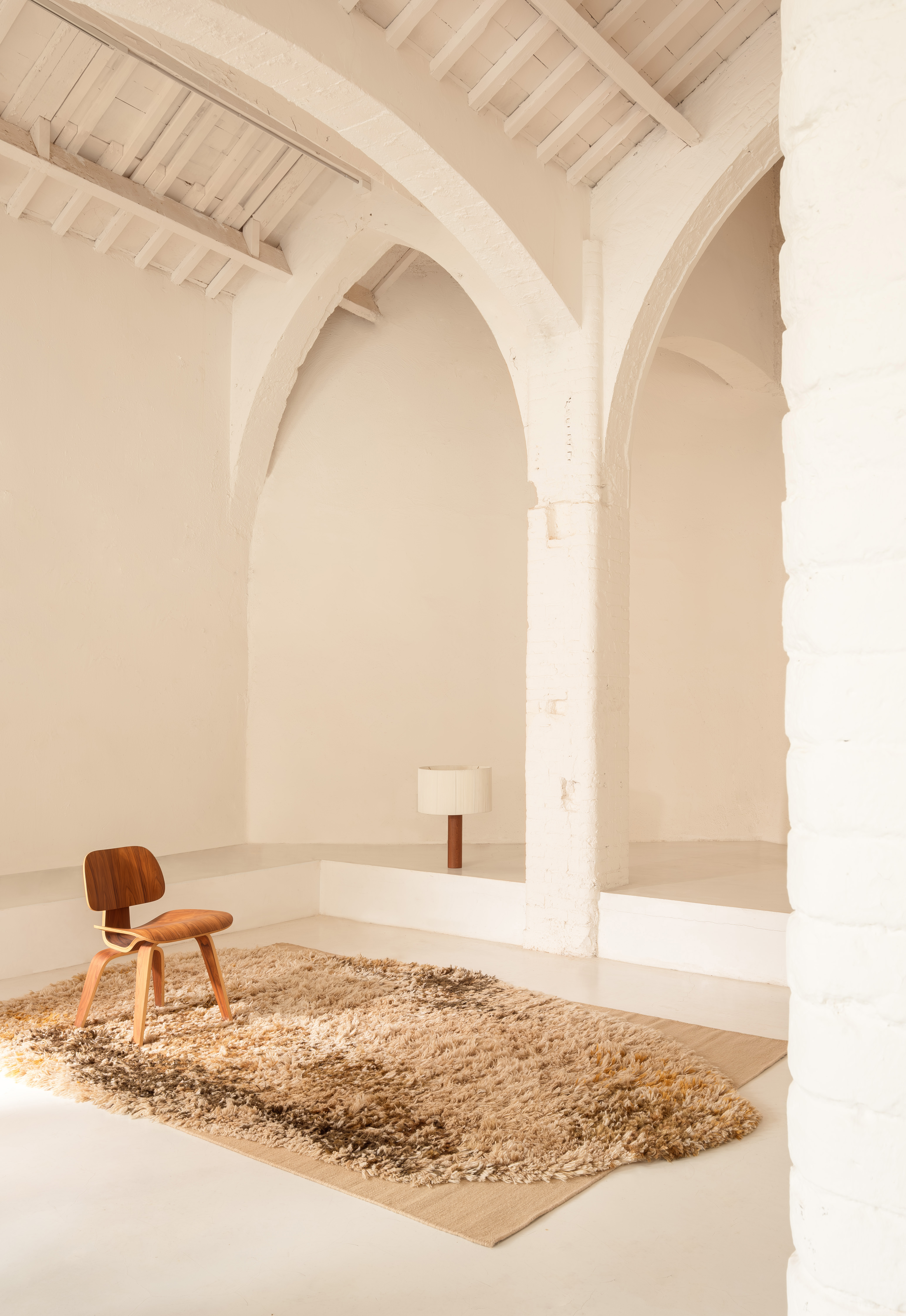 Nanimarquina Alga Rug Teppich in beiger Farbgebung mit Stuhl und Lampe in hellem Raum.