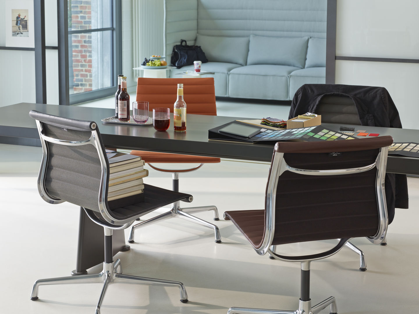 Detailaufnahme von Vitra Aluminium Chairs EA 104 in Grau und Braun an einem Konferenztisch.