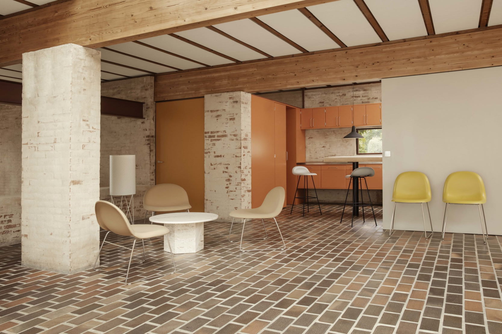 Innenraum mit Gubi Epic Couchtisch, Stühlen und Backsteinboden. Moderner Wohnraum mit Designermöbeln.