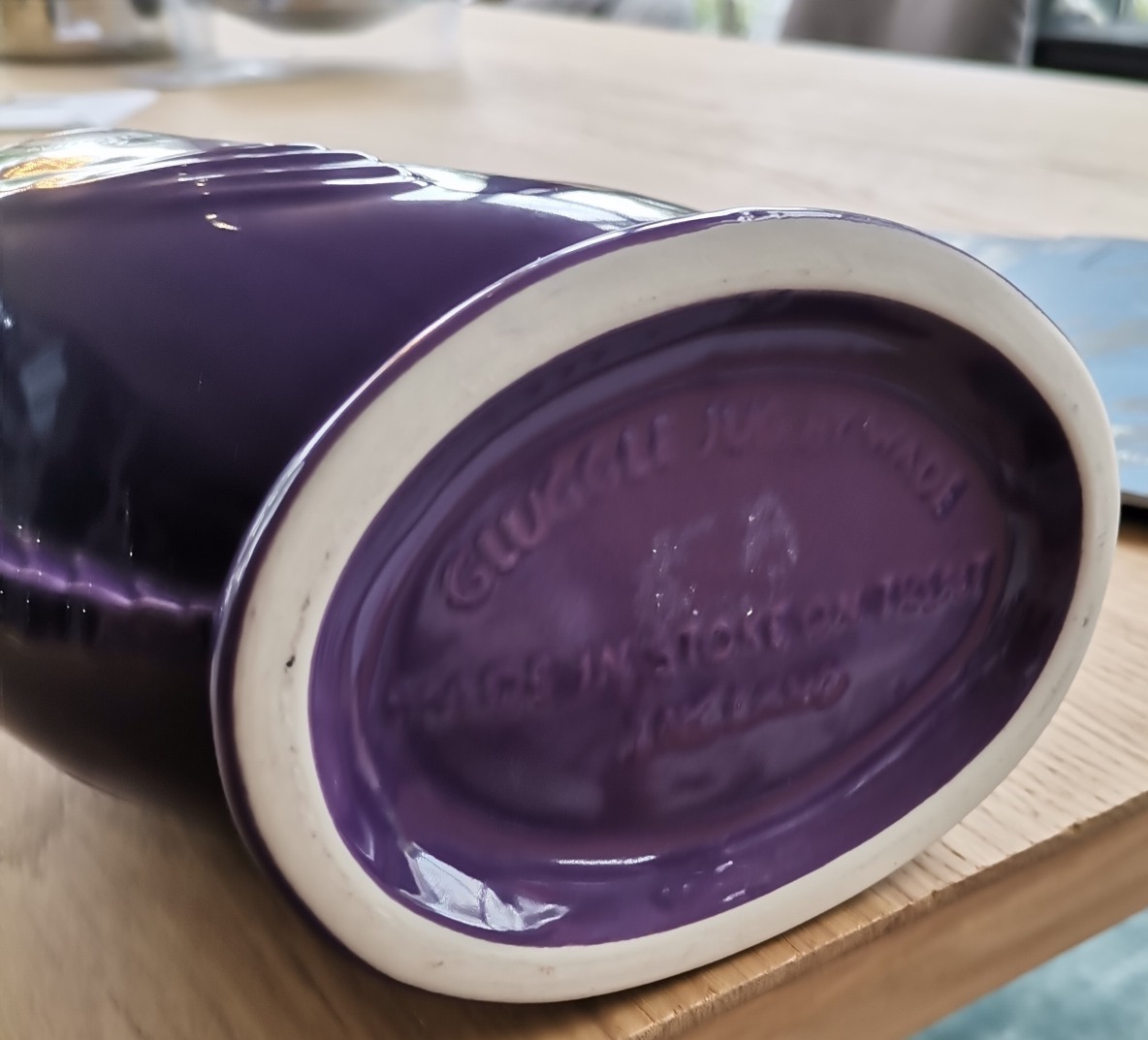 Detailaufnahme des Bodens einer lila Gluckigluck Karaffe, hergestellt in England. Keramikvase mit Prägung.