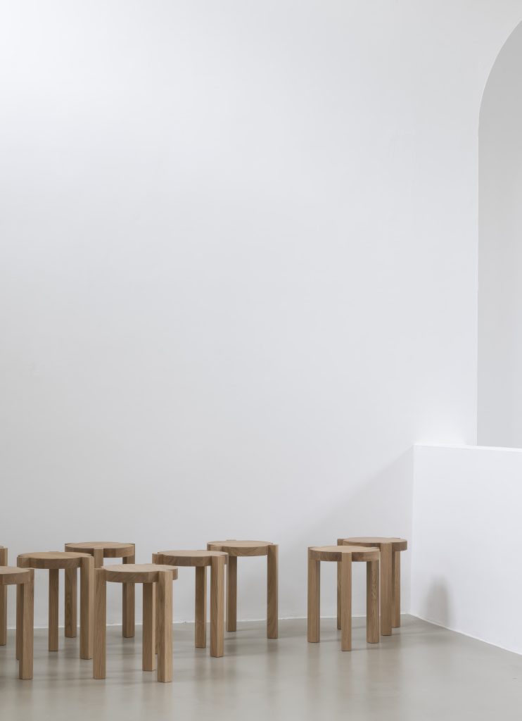 Mehrere Ayo Hocker von New Tendency aus hellem Holz vor weißem Hintergrund.