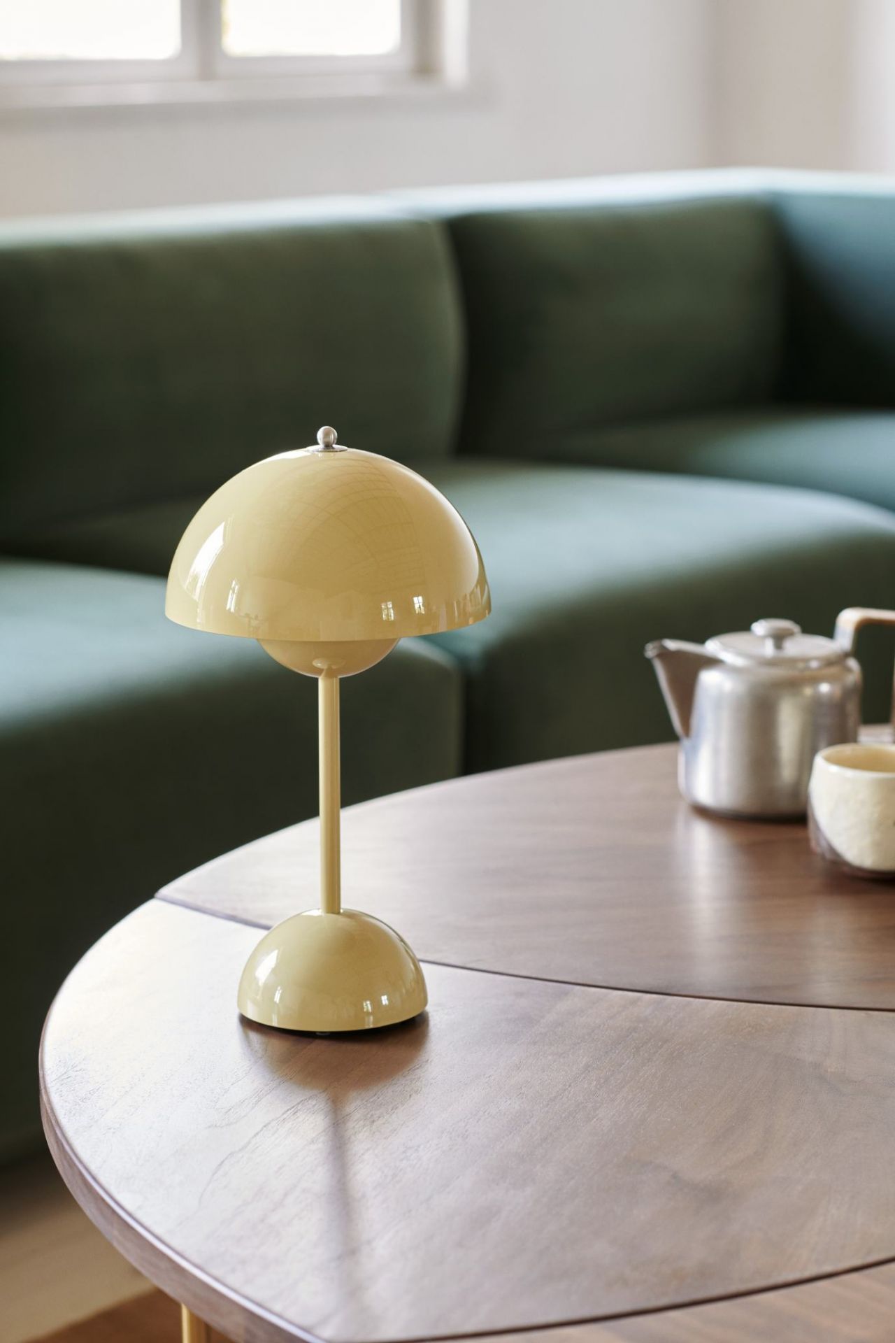 Gelbe Tischleuchte im Retro-Design auf einem Holztisch, neben Teekanne und Tasse, für gemütliche Beleuchtung.