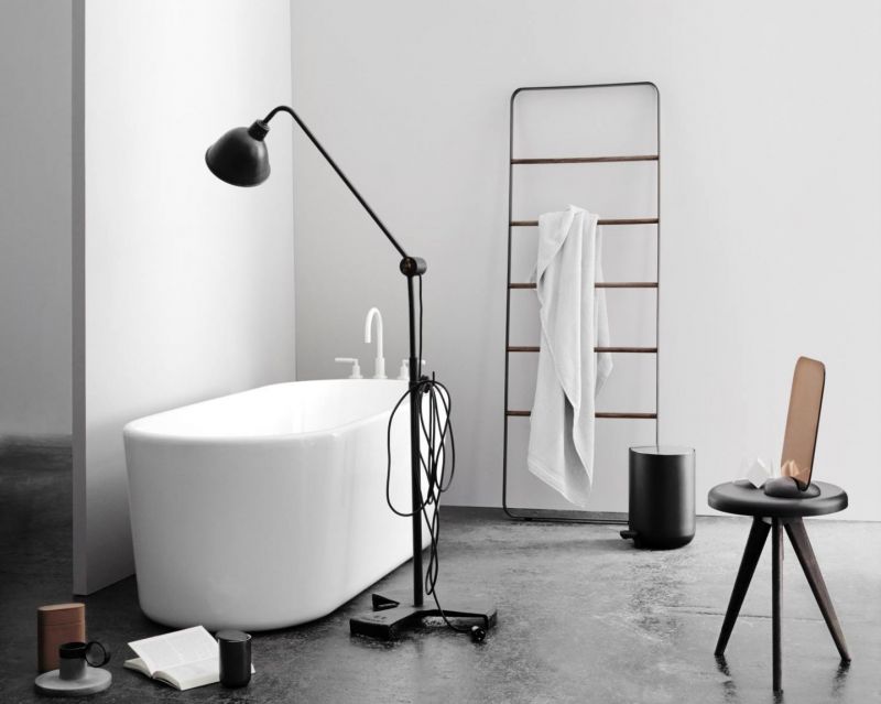 Modernes Badezimmer mit freistehender Badewanne, Handtuchleiter, schwarzem Mülleimer und Stehlampe für stilvolle Badezimmergestaltung.