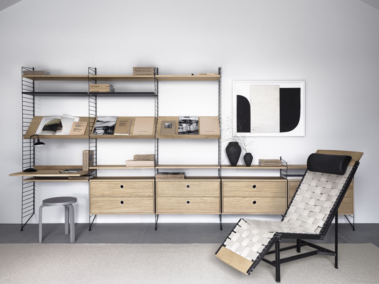 Wohnzimmer mit String Furniture Regalsystem, bestehend aus Bodenleitern in Schwarz und Holzregalen.