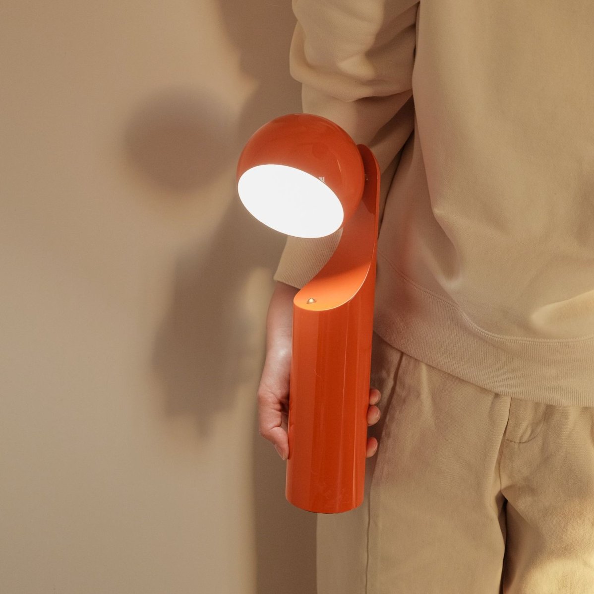Person hält die orangefarbene Mono Akkuleuchte / Tischleuchte von house of home.