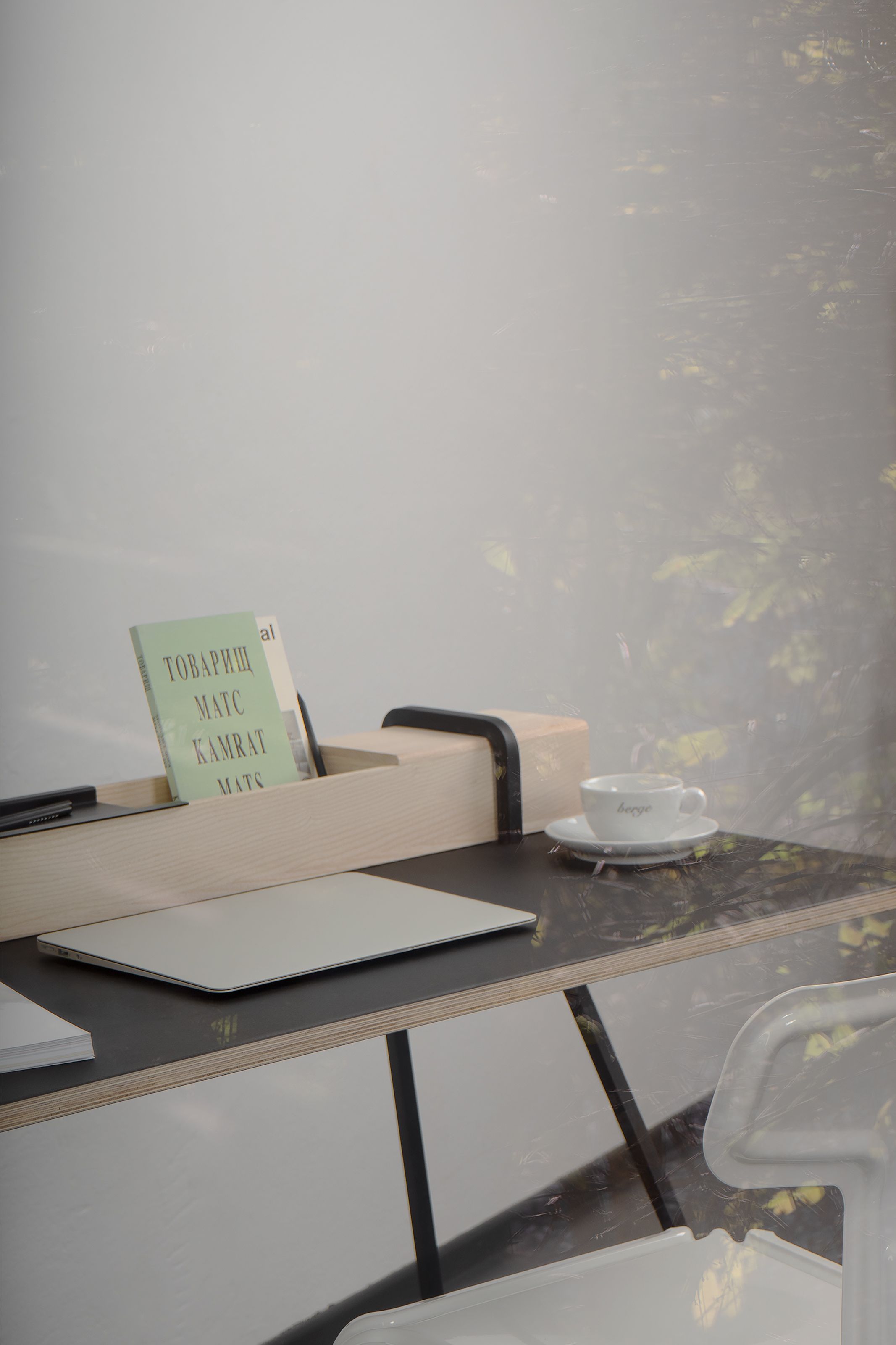 Kurt Sekretär von Nils Holger Moormann mit Laptop, Buch und Kaffeetasse auf dem Schreibtisch.