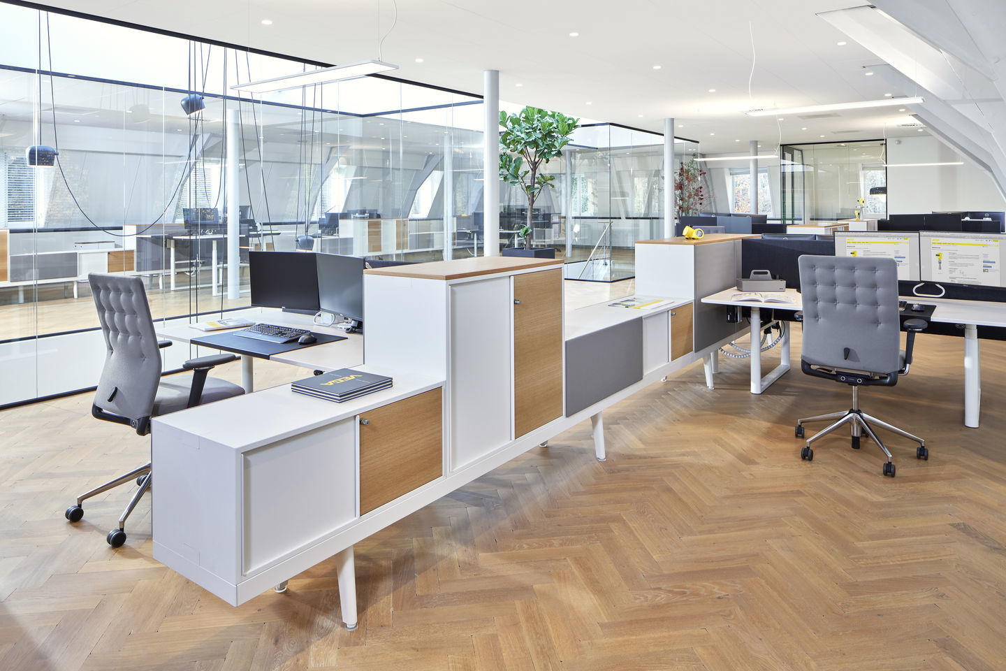 Helles Büro mit mehreren Arbeitsplätzen und grauem ID Trim Bürodrehstuhl von Vitra mit gepolsterter Rückenlehne.
