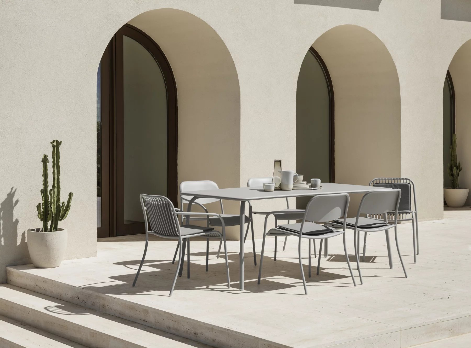 Blomus Yua Wire Armchair Outdoor: Graue Armlehnstühle und Tisch auf einer Terrasse mit minimalistischem Design.