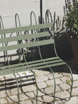 Nahaufnahme der grünen Gardener's Sofa Gartenbank von Design House Stockholm auf Pflastersteinen im Außenbereich.
