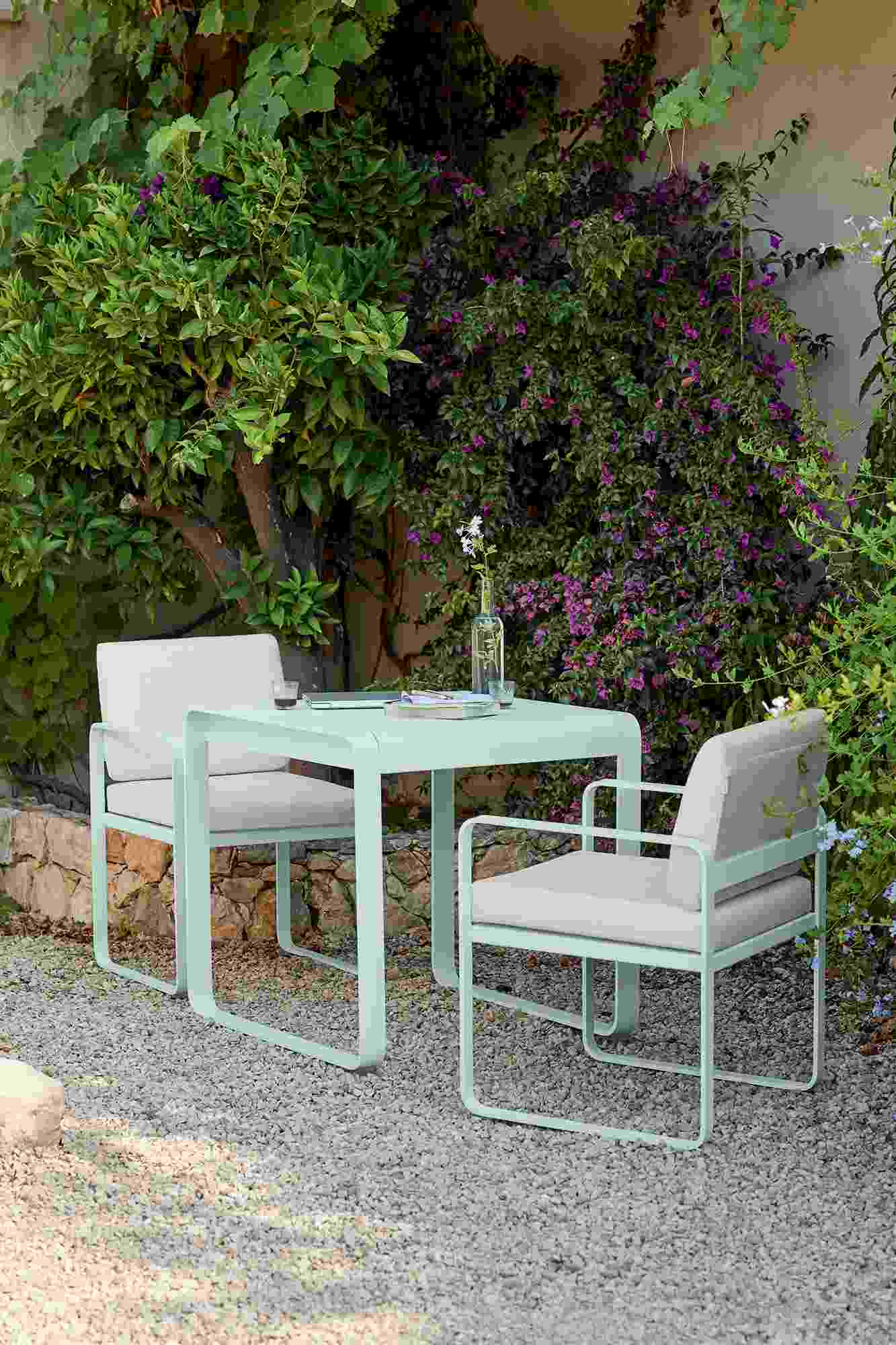 Bellevie Outdoor Tisch und Stühle von Fermob in Mintgrün im Garten auf Kies.