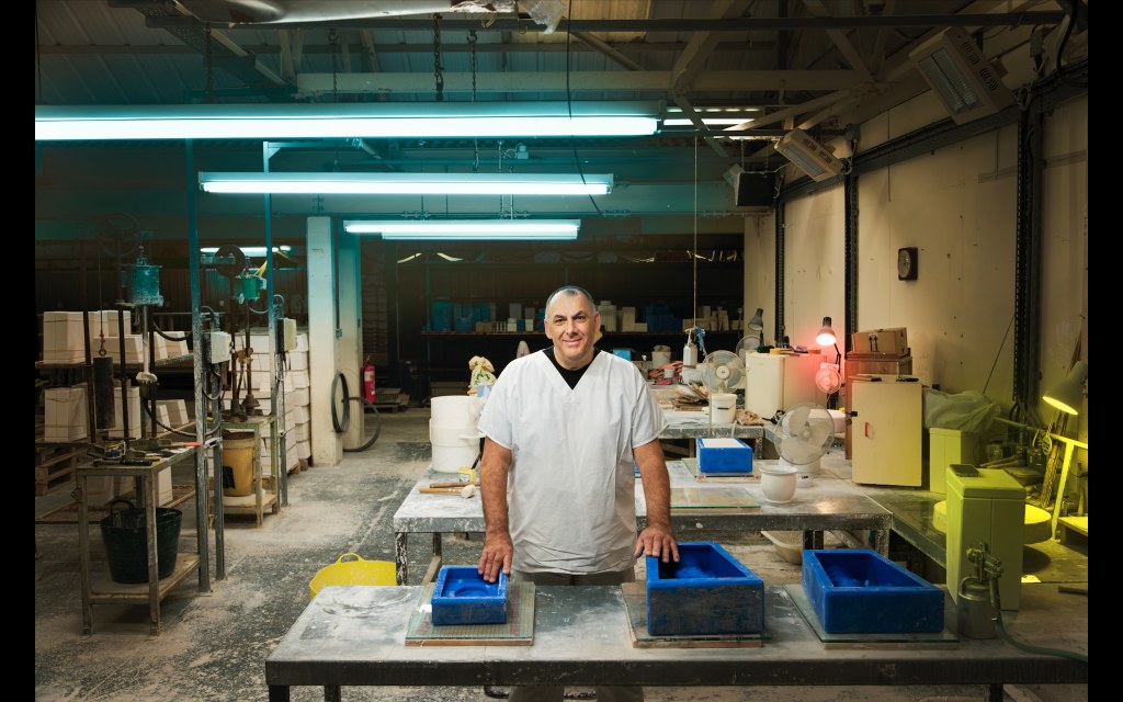 Handwerker in Werkstatt, der blaue Gussformen für Keramik, möglicherweise Gluckigluck Karaffen, vorbereitet.