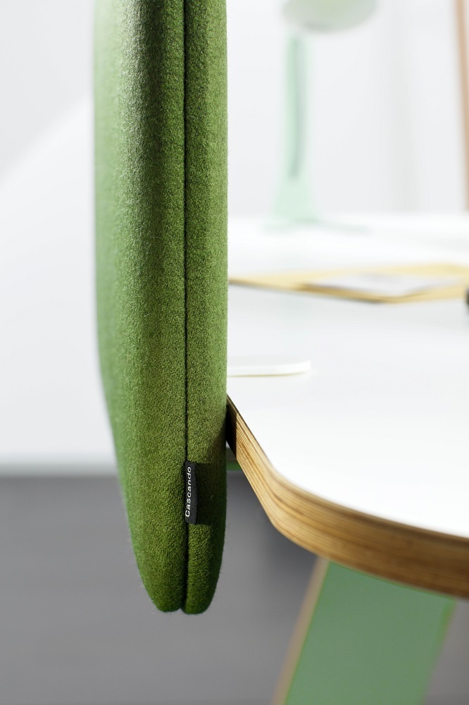 Nahaufnahme eines grünen Cascando Pillow Desk Akustikelements am Schreibtisch zur Schallabsorption im Büro.