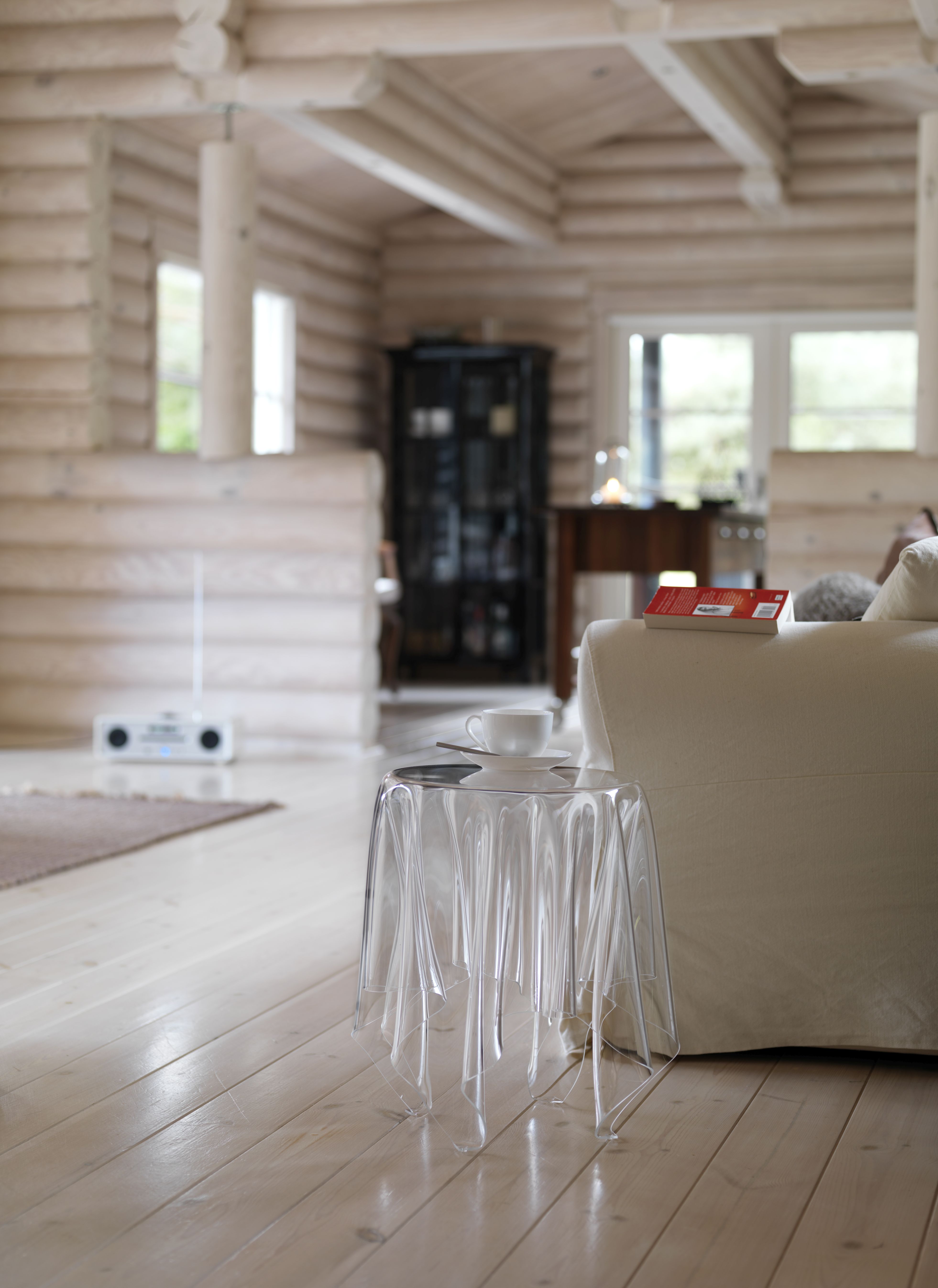 Transparenter Essey Illusion Beistelltisch neben Sofa mit Tasse in hellem Wohnzimmer.