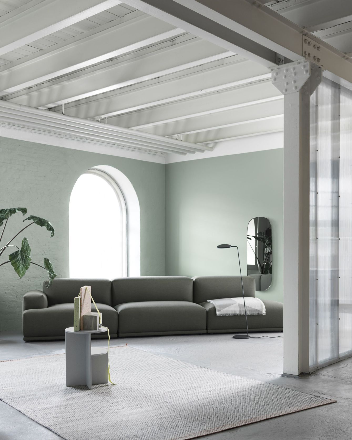 Graues modulares Sofa im modernen Wohnzimmer mit Teppich, Beistelltisch und Stehlampe.