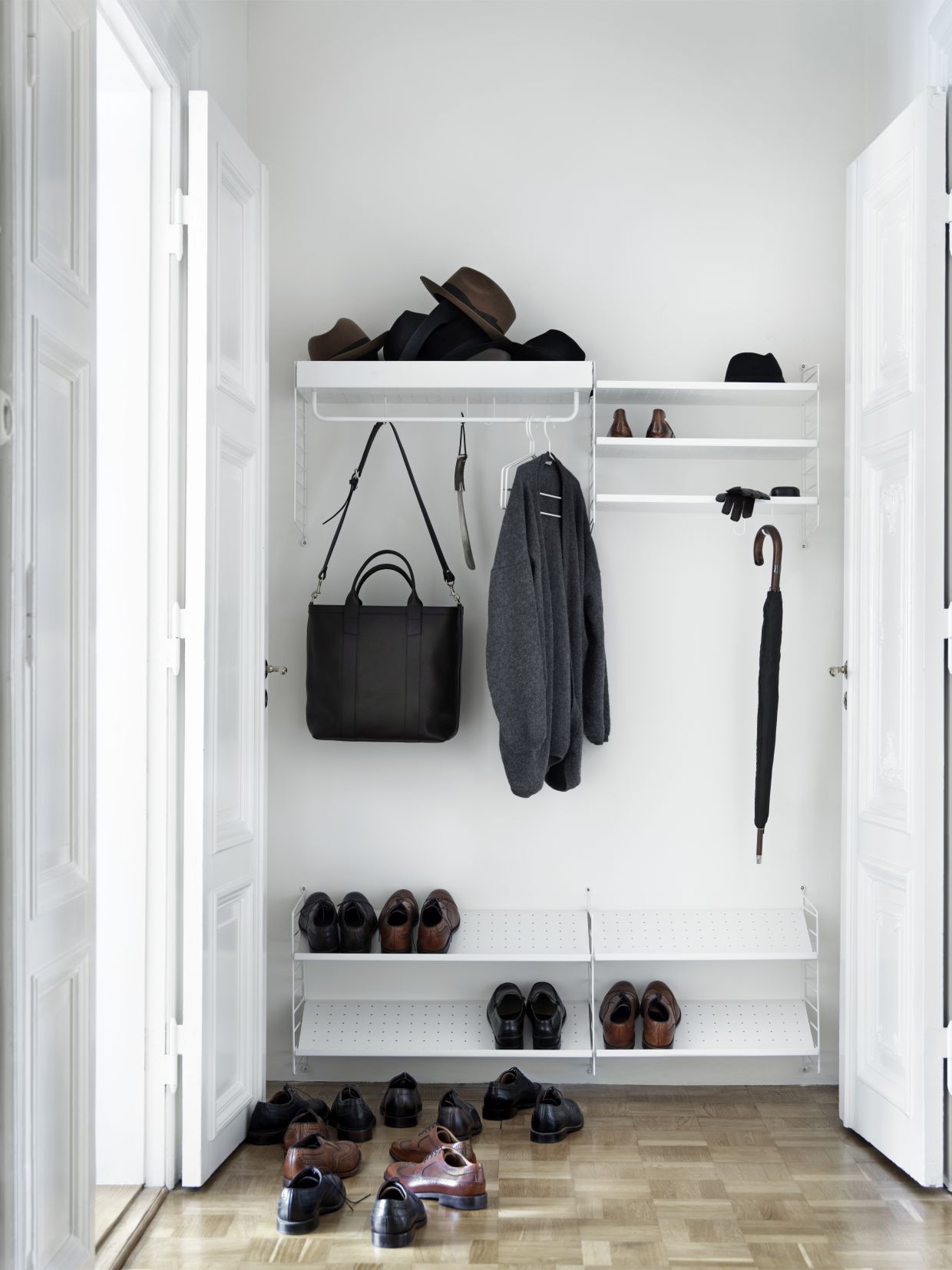 Eingangsbereich mit String Regalsystem: Kleidung, Schuhe, Taschen und Einzelteil Kleiderbügel sind sichtbar.