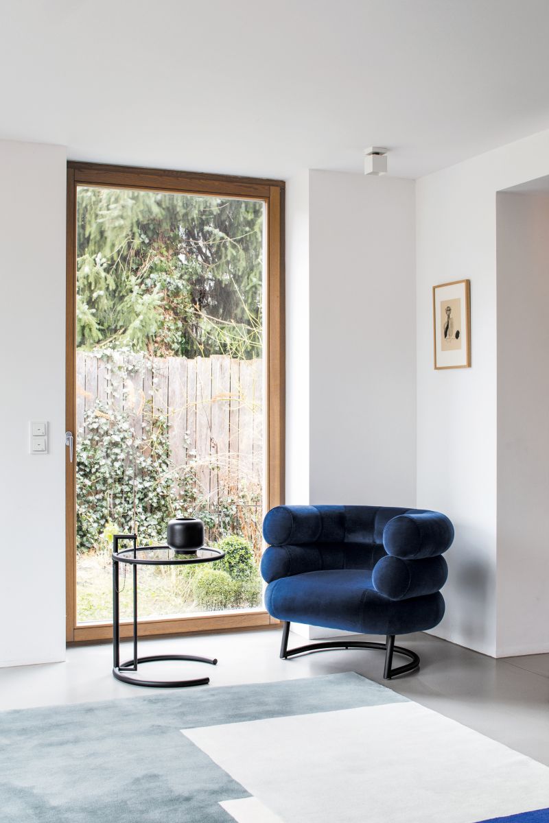 Blauer Sessel mit Roquebrune Teppich von ClassiCon und Beistelltisch in modernem Wohnzimmer.