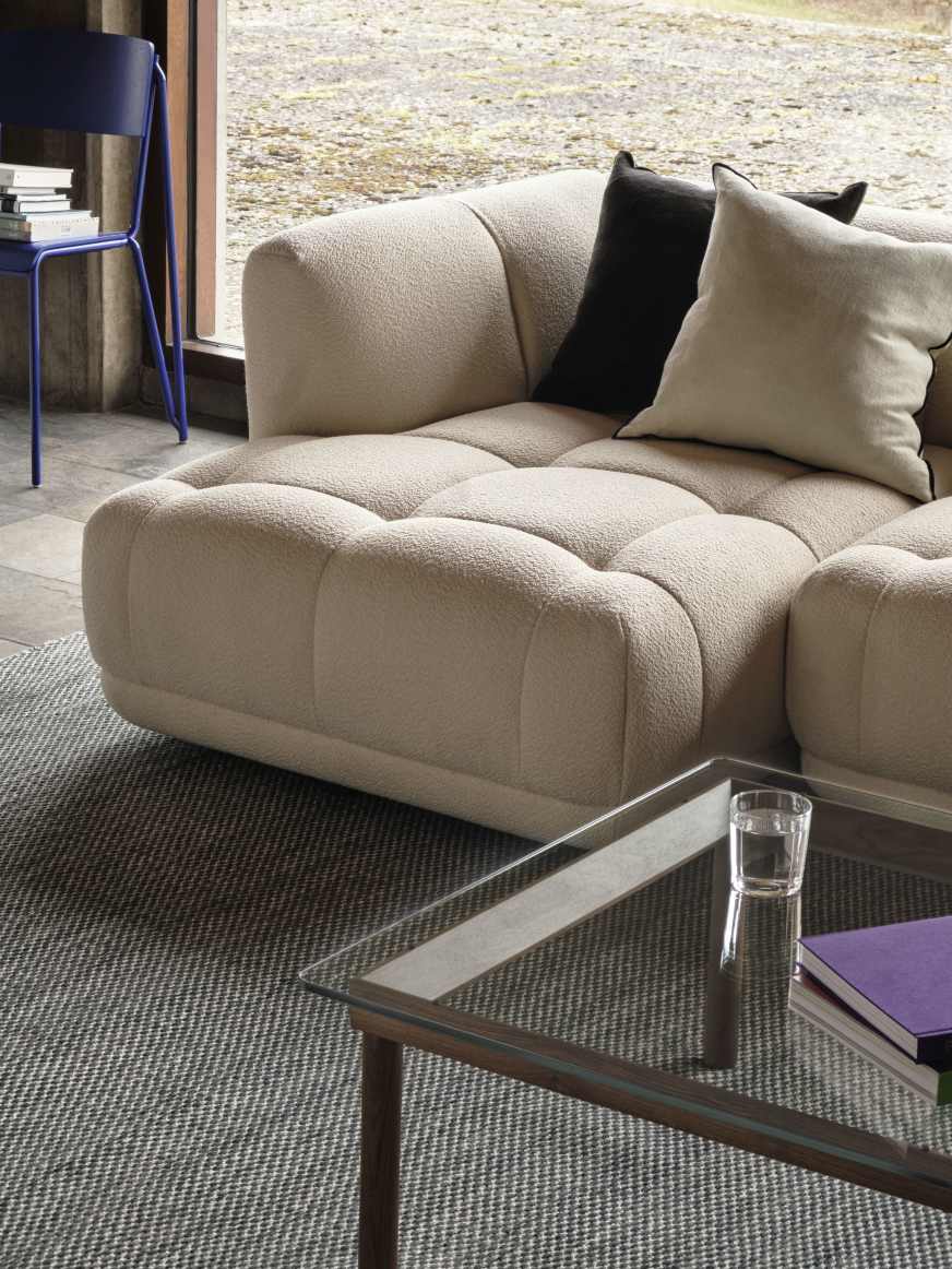 Nahaufnahme des Kofi Couchtisches von Hay mit Walnussgestell und Klarglasplatte im Wohnzimmer.