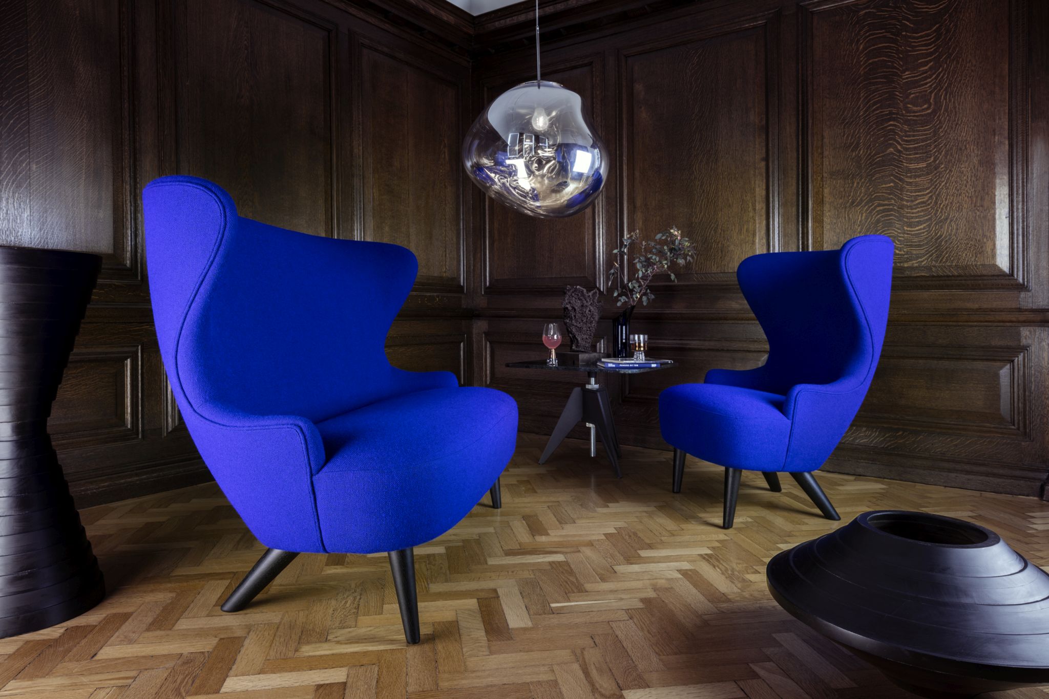 Zwei blaue Sessel mit hoher Rückenlehne und Design Lampe in einem stilvollen Wohnzimmer.