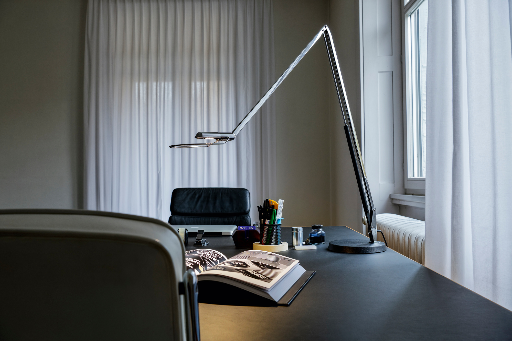 Liftolino LED Tischleuchte von Belux auf einem Schreibtisch, dimmbare Arbeitsplatzleuchte aus Aluminium.