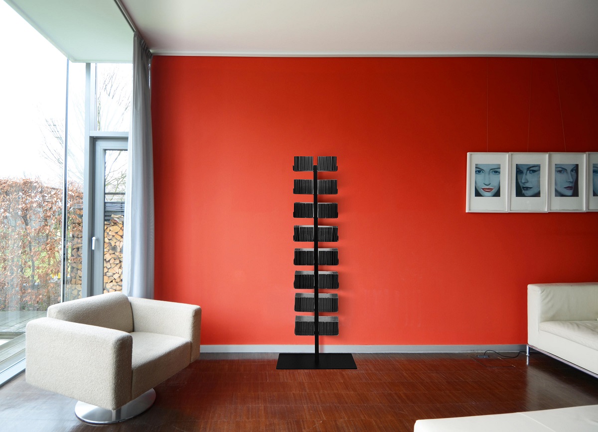 Schwarzer CD-Baum / DVD-Baum im modernen Wohnzimmer vor roter Wand. Regal für CDs und DVDs.