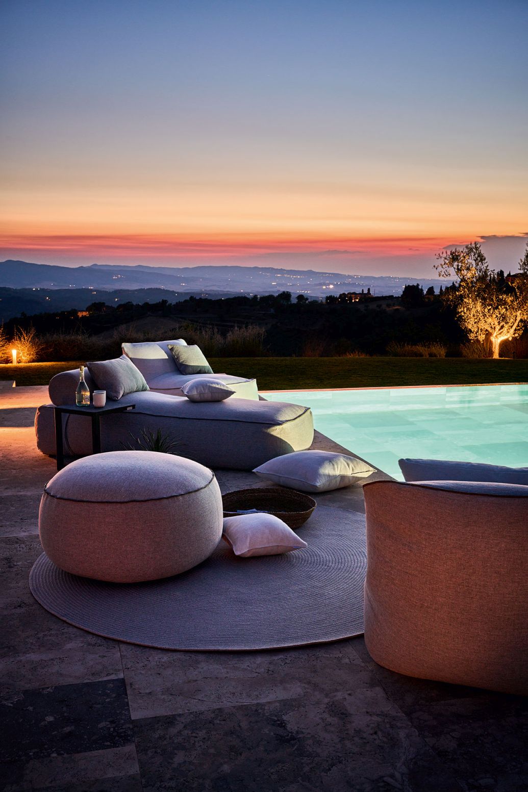 Maliha Lounge Bett Outdoor Weishäupl Pebble am Pool bei Sonnenuntergang. Luxuriöse Outdoor-Möbel für entspannte Stunden.