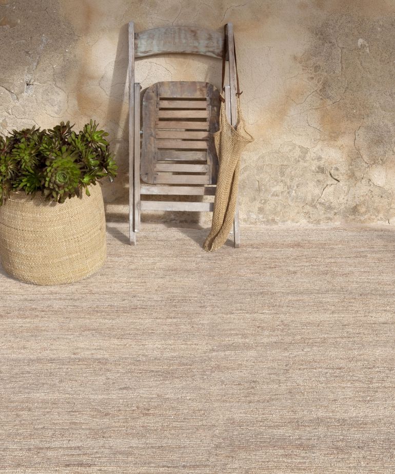 Nanimarquina Earth Rug Teppich, beige Naturfaser Teppich im Innenbereich mit Stuhl und Pflanze.