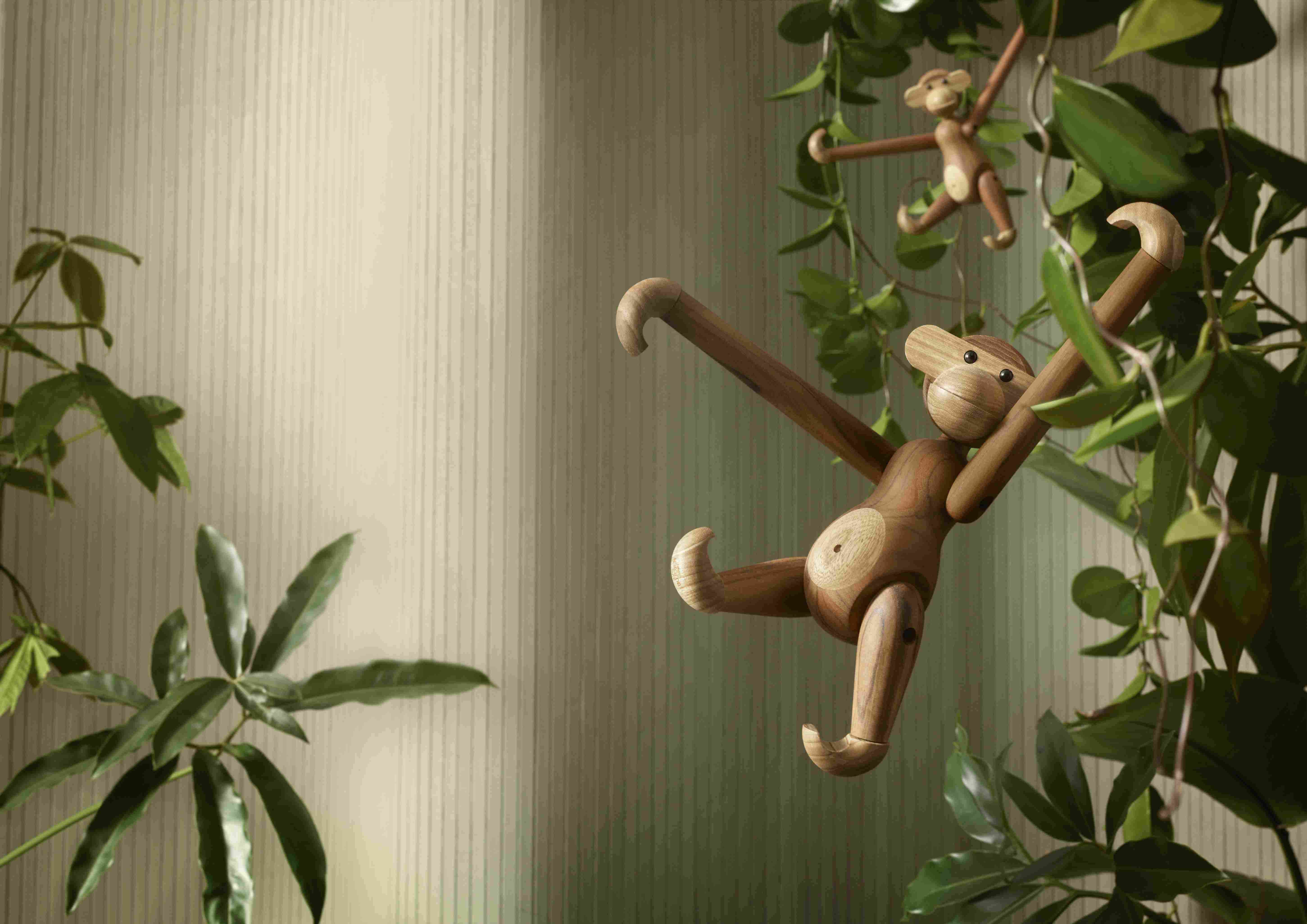 Hölzerner Affe als Deko-Objekt zwischen grünen Pflanzen, skandinavisches Design für Kinderzimmer und Wohnraum.