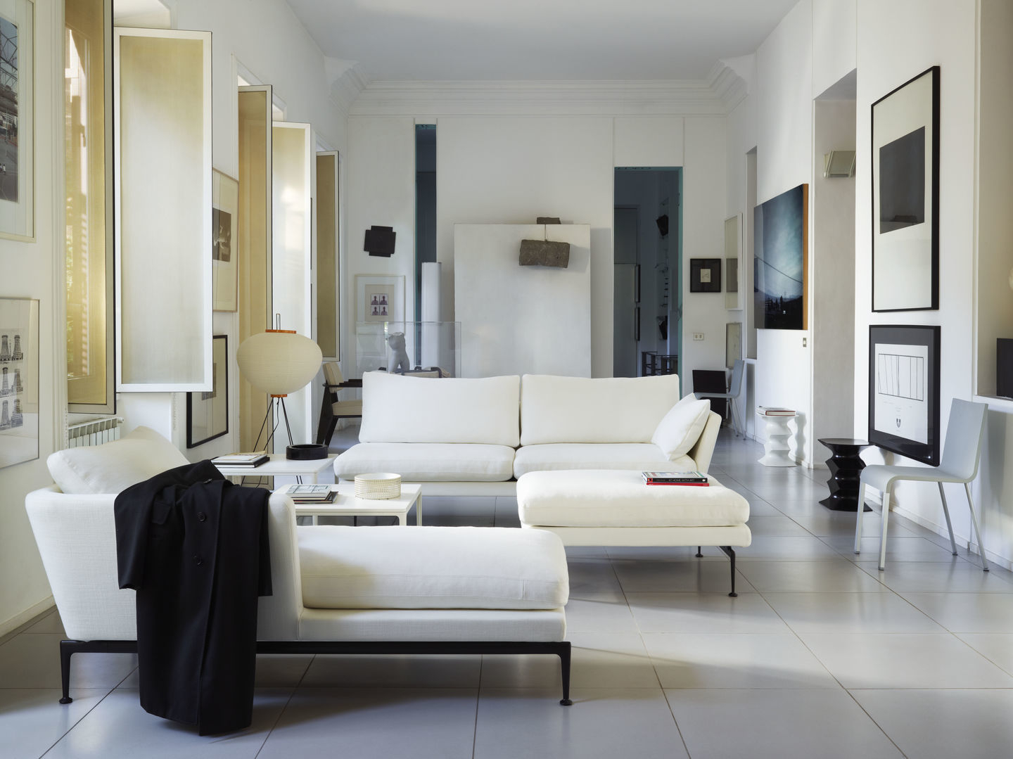 Heller Wohnraum mit Vitra .03 Stuhl, weißen Sofas und moderner Kunst. Designermöbel für stilvolles Wohnen.